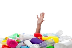 Environment concept with human hand reaching out from beneath plastic recipients