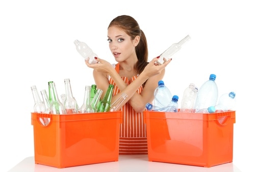 Young girl sorting glass and plastic bottles isolated on white