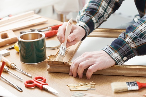 Man varnishing a wooden frame at home