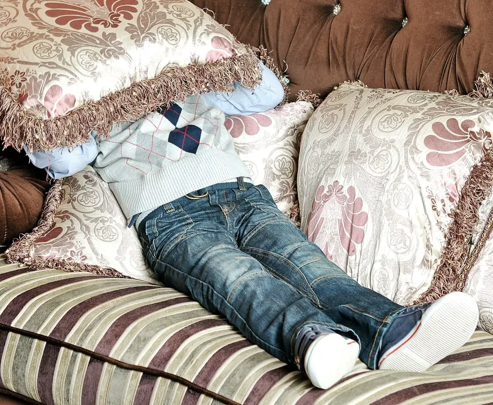 boy covers his face with a pillow