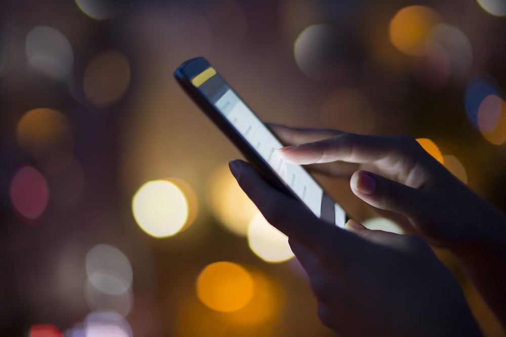 Woman using her mobile phone , city skyline night light backgro