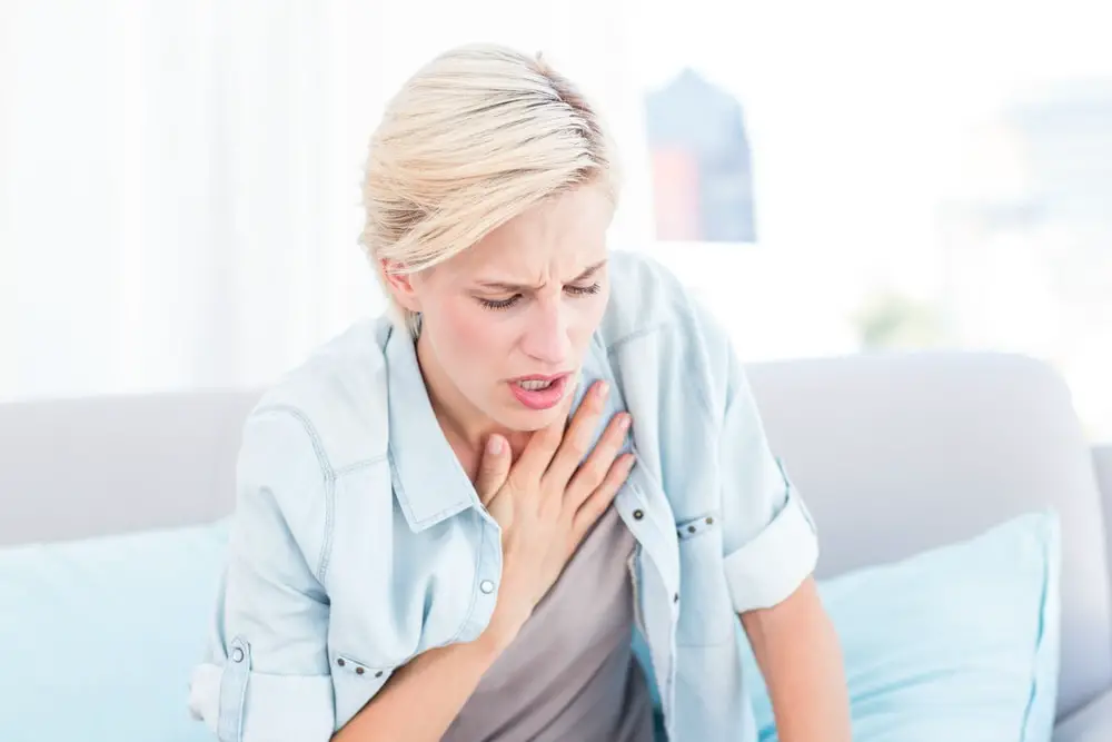 Pretty blonde woman having breath difficulties in the living room