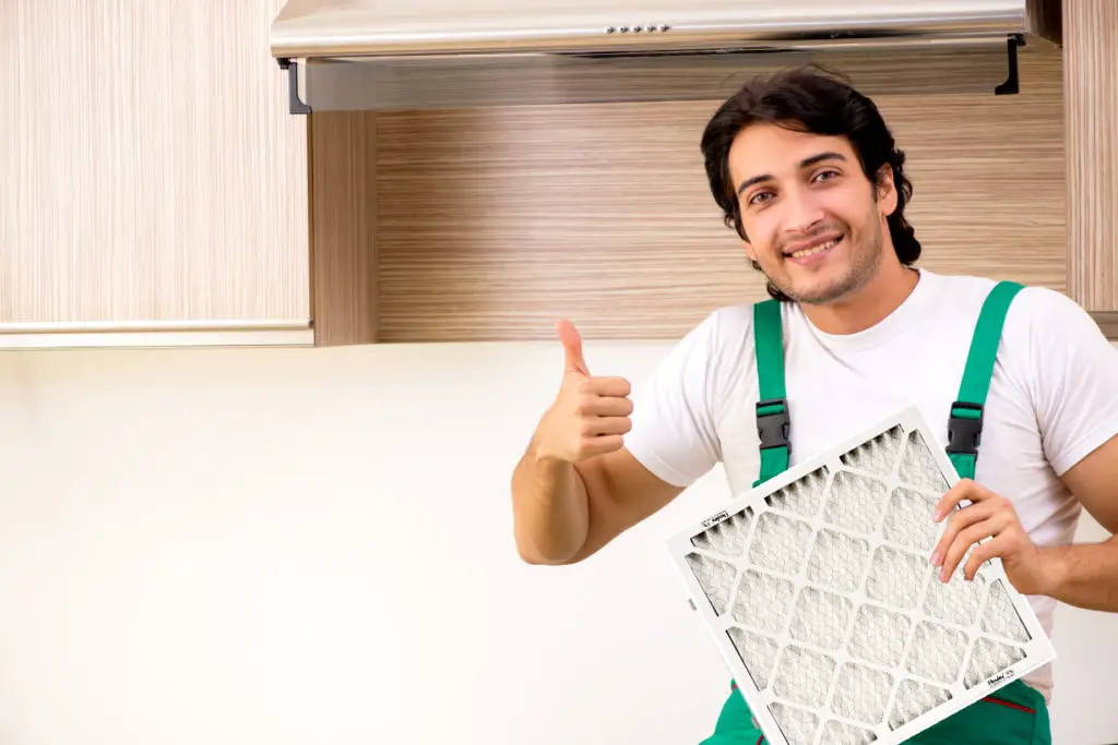 Handyman holding a furnace filter with thumbs up