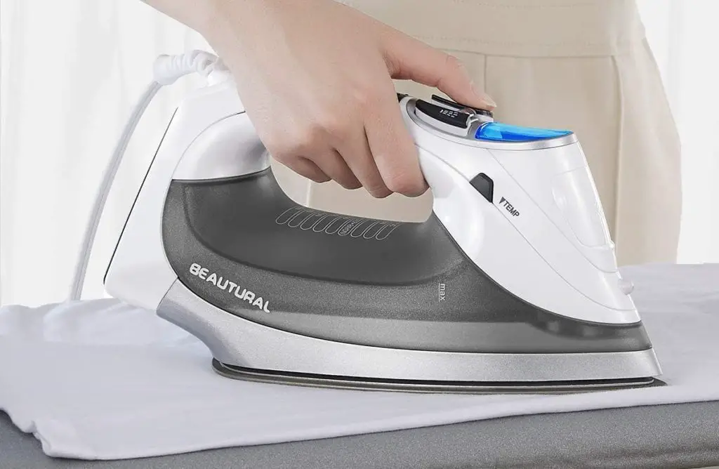 Woman hands ironing fabric on table