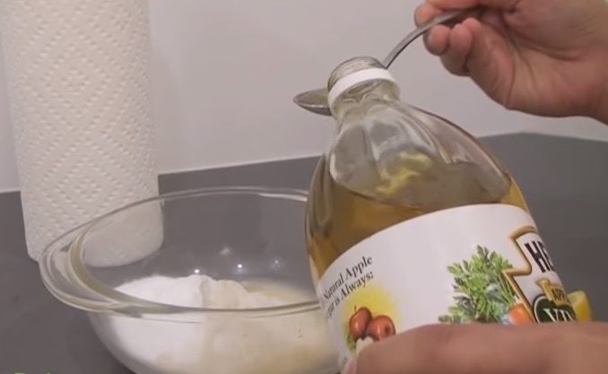 Pouring vinegar to tablespoon and mixing bowl with baking soda