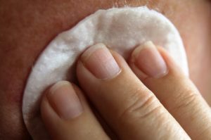 Woman's hand with cotton wiping on her face