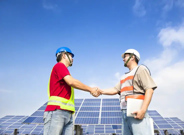 two engineers handshaking before large solar power station