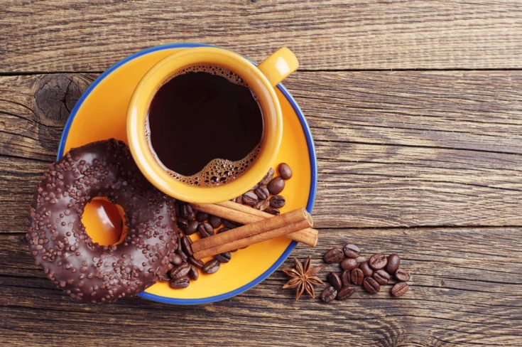 Chocolate donut and cup of hot coffee on vintage wooden table. Top view